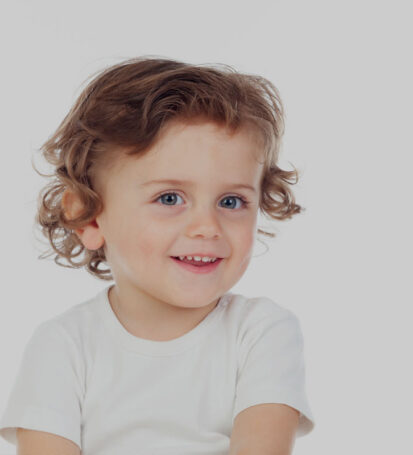 young toddler smiling showing baby teeth wearing white shirt